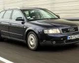 Ciemnogranatowe Audi B6 Avant pędzi autostradą. Kierowca skupiony na drodze.