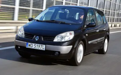 Czarny Renault Scenic 2 1.6 16v jedzie autostradą. Kierowca w okularach przeciwsłonecznych prowadzi auto.