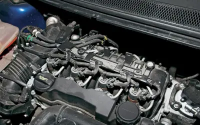 Silnik Volvo V50 1.6 diesel z widocznymi wtryskiwaczami, przewodami i zbiorniczkiem płynu chłodniczego.