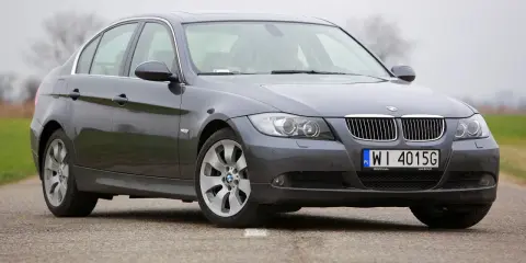 Szary sedan BMW E90 2.0 benzyna na drodze.