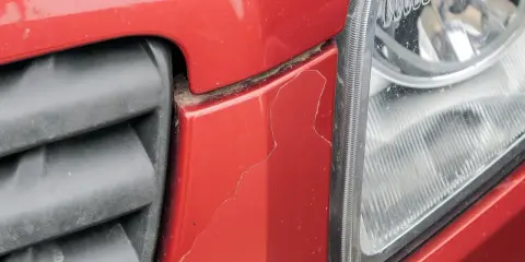Pęknięty czerwony zderzak obok reflektora. Czas sprawdzić malowanie zderzaka cena.