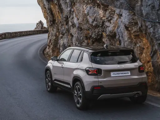 Nowy Jeep Avenger, jeden z najnowszych jeep modele, pokonuje krętą drogę nad morzem, wspinając się po skalistym zboczu.