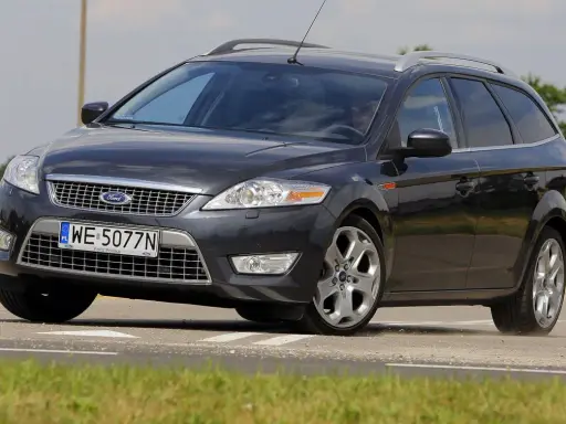 Ciemnoszary Ford Mondeo MK4 2.0 TDCI na drodze, z widocznym polem zboża w tle.