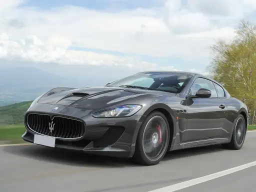 Szary Maserati GranTurismo na krętej drodze. Marzysz o takim aucie? Sprawdź, jaka jest aktualna maserati cena!