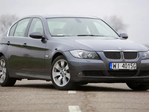 Szary sedan BMW E90 2.0 benzyna na drodze.