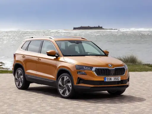 Pomarańczowy Skoda Karoq na tle morza. Sprawdź aktualną skoda karoq cena i wybierz swój wymarzony SUV.