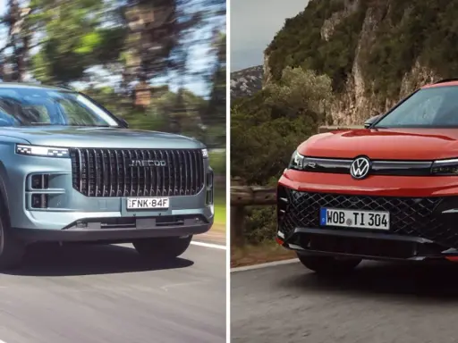 Dwa SUV-y na drodze: szary z pionową atrapą i czerwony Volkswagen SUV z charakterystycznym logo.
