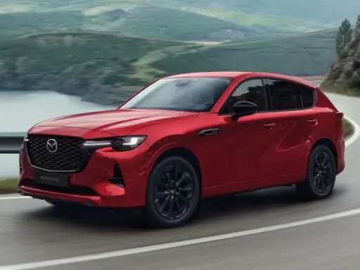 Czerwona Mazda CX-60 3.3 Diesel pokonuje zakręt na malowniczej drodze.