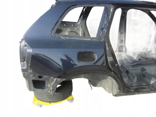 Tylna część nadwozia Volvo XC90 w kolorze granatowym, bez szyb i wnętrza, na żółtym wózku.