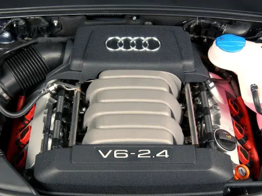 Silnik V6 2.4 z Audi C6. Widoczne logo Audi i elementy układu zapłonowego.