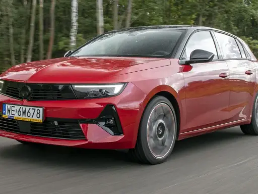 Czerwony Opel Astra Turbo pędzi leśną drogą.