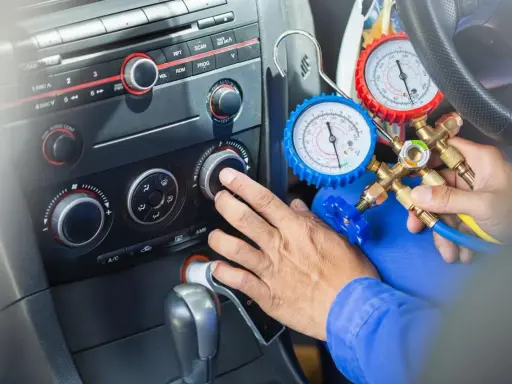 Mechanik sprawdza, ile czynnika do klimatyzacji pozostało w samochodzie, używając manometrów.