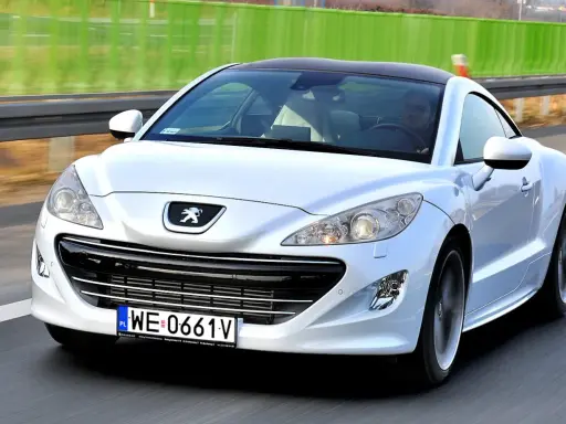 Biały Peugeot RCZ, jeden z francuskich marek samochodów, pędzi po autostradzie.