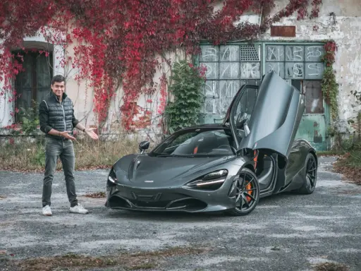 Mężczyzna prezentuje szarego McLarena 720S z otwartymi drzwiami. Zastanawiasz się nad mclaren 720s cena?