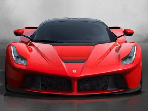 Przód czerwonego LaFerrari z czarnym dachem i przyciemnianymi szybami, błyszczący na tle szarej ściany.