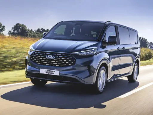 Ciemnoniebieski ford 7 osobowy Tourneo Custom pędzi po drodze wśród pól.
