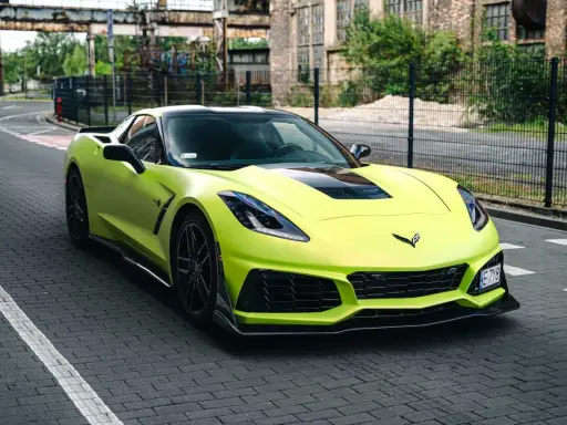 Jasnozielony Chevrolet Corvette C7 na brukowanej drodze. Zastanawiasz się nad corvette c7 cena?