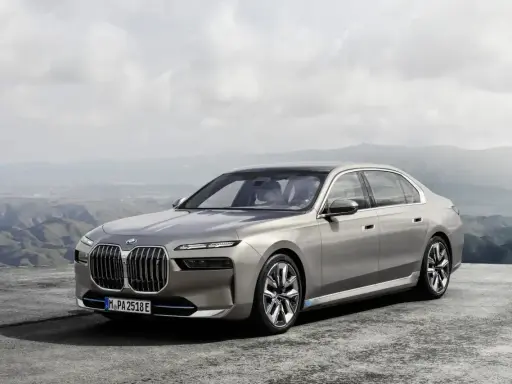 Eleganckie, srebrne BMW 7 2025 z niebieskimi akcentami na felgach, zaparkowane na tle górskiego krajobrazu.