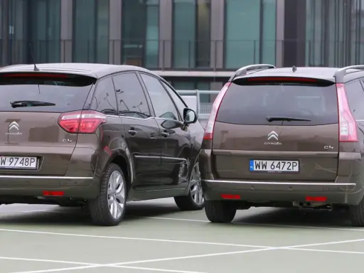 Dwa brązowe Citroen Grand Picasso stoją obok siebie na parkingu.