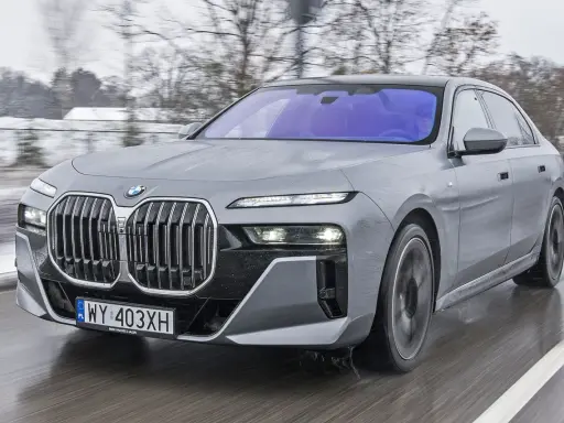 Szare BMW Serii 7 w ruchu, z widocznym grillem i światłami. Sprawdź aktualną bmw 7 cena.