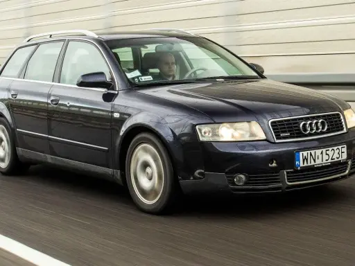 Ciemnogranatowe Audi B6 Avant pędzi autostradą. Kierowca skupiony na drodze.