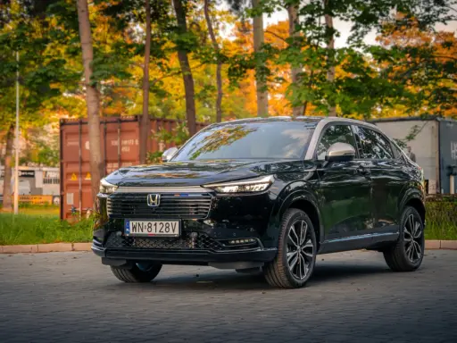 Elegancki, czarny Honda HR-V 2025 na tle jesiennych drzew i kontenerów.
