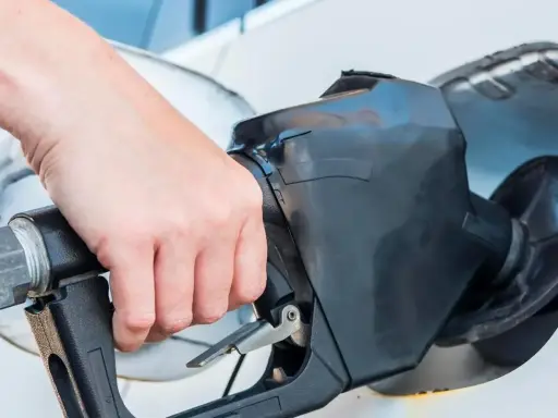 Dłoń trzyma pistolet paliwowy, rozpoczynając tankowanie samochodu.