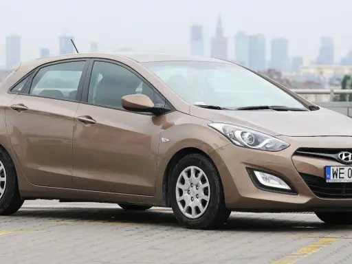 Brązowy Hyundai i30 1.6 benzyna na parkingu z widokiem na miasto w tle.