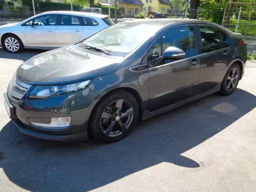Ciemnoszary Chevrolet Volt stoi na parkingu. Obok niego widać srebrne kombi.