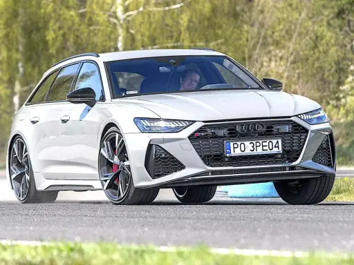Białe Audi RS6 Avant na torze, kierowca wpatrzony przed siebie.