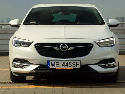 Biały Opel Insignia 2.0 Turbo z polskimi tablicami WE 445SF zaparkowany na dachu.