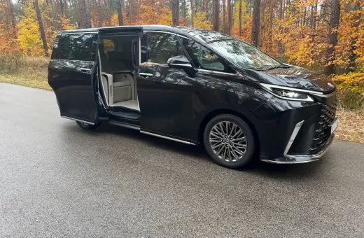 Elegancki Lexus LM 350h z otwartymi drzwiami, zapraszający do luksusowego wnętrza, na tle jesiennego lasu.