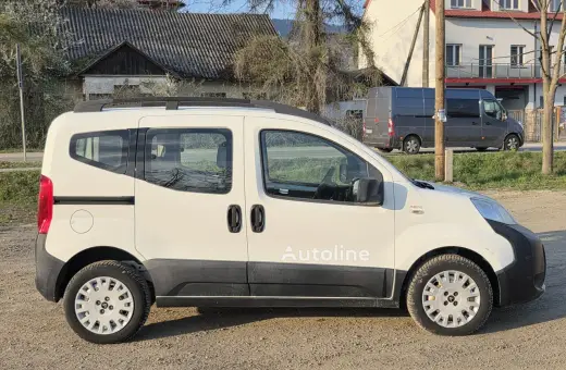 Biały Citroen Nemo z napisem "Autoline" stoi na żwirowej drodze. W tle widać domy i szare furgonetki.