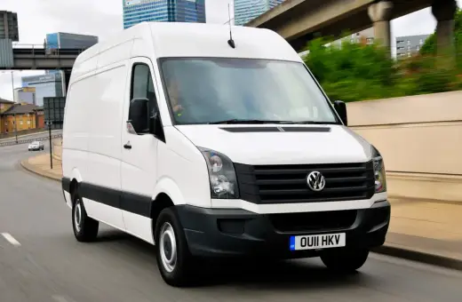 Biały Volkswagen Crafter w ruchu miejskim, z kierowcą za kierownicą.