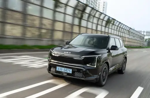 Nowoczesne kia ev5 w kolorze czarnym jedzie po drodze, mijając dźwiękochłonne bariery.