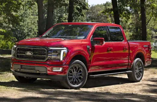Czerwony Ford F-150 z czarnymi felgami stoi na leśnej ścieżce, gotowy na przygodę.