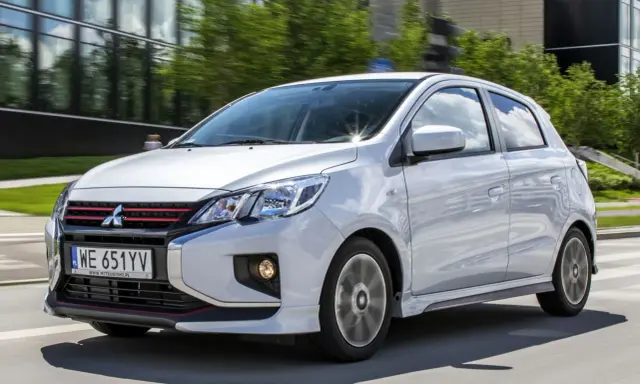 Srebrny Mitsubishi Space Star z czerwonymi akcentami na grillu i zderzaku jedzie po drodze.