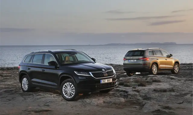 Dwa SUV-y Skoda Kodiaq 2024 na skalistym wybrzeżu. Jeden czarny, drugi w kolorze złota.