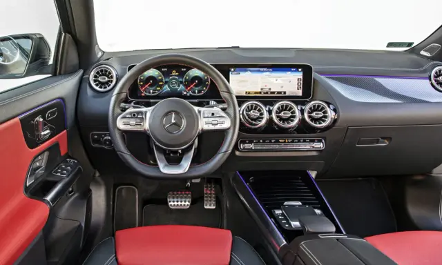Wnętrze Mercedesa GLA 200 z czerwono-czarną tapicerką, nowoczesnym kokpitem i ekranem nawigacji.