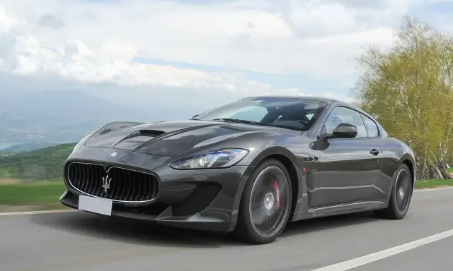 Szary Maserati GranTurismo na krętej drodze. Marzysz o takim aucie? Sprawdź, jaka jest aktualna maserati cena!