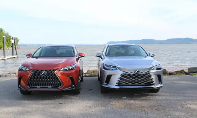 Dwa lśniące suvy Lexus stoją obok siebie nad wodą.