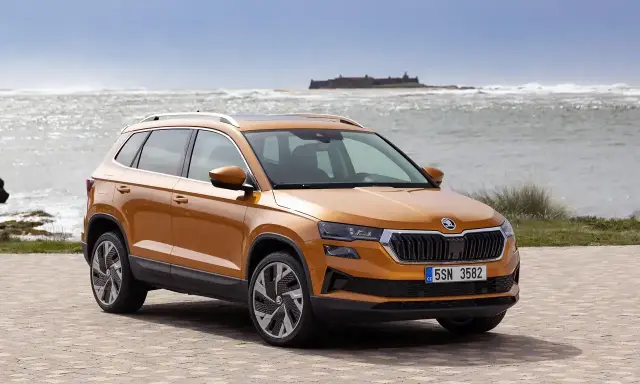 Pomarańczowy Skoda Karoq na tle morza. Sprawdź aktualną skoda karoq cena i wybierz swój wymarzony SUV.
