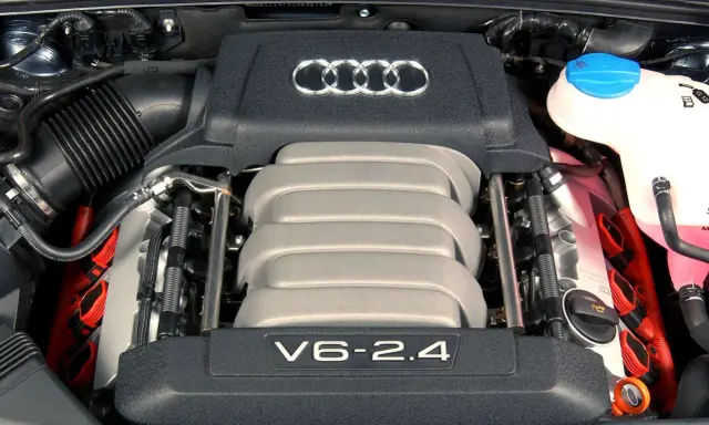 Silnik V6 2.4 z Audi C6. Widoczne logo Audi i elementy układu zapłonowego.