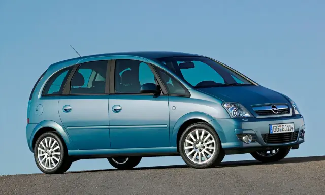 Błękitny Opel Meriva A z przyciemnianymi szybami stoi na tle błękitnego nieba.