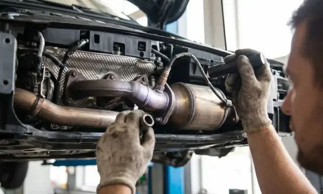 Mechanik sprawdza układ wydechowy Toyoty, potencjalnie diagnozując błąd DTC P0420.
