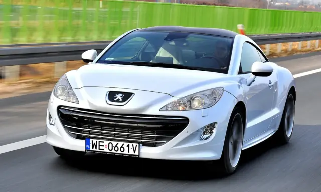 Biały Peugeot RCZ, jeden z francuskich marek samochodów, pędzi po autostradzie.