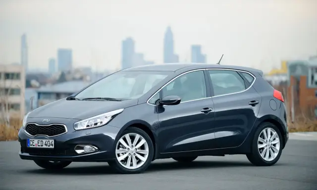 Ciemnoszary Kia Ceed 1.6 benzyna stoi na tle miejskiego krajobrazu.