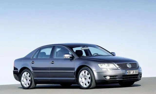 Elegancki, ciemnoszary VW Phaeton W12 z lat 2002-2006 prezentuje się na tle błękitnego nieba.