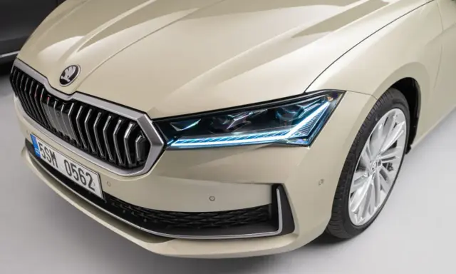 Nowy Skoda Superb 2024 w beżowym kolorze, z charakterystycznym grillem i nowoczesnymi światłami LED.