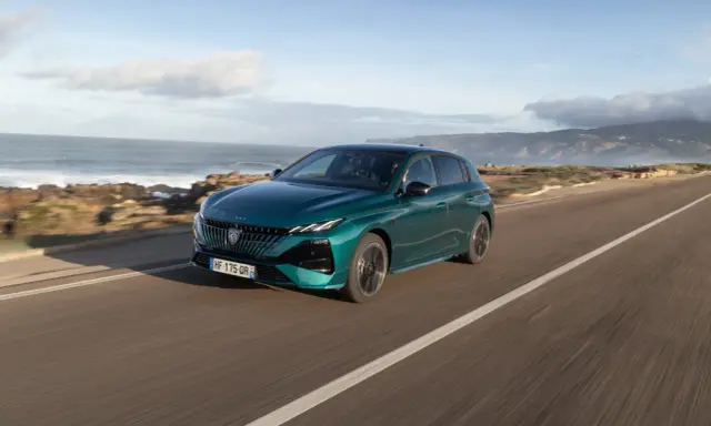 Zielony Peugeot 308 jedzie wzdłuż malowniczego wybrzeża.